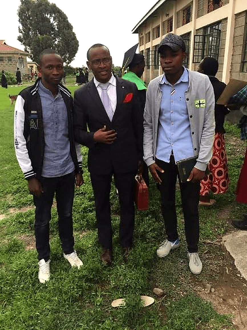 Founder with two young men he has mentored, dressed formally